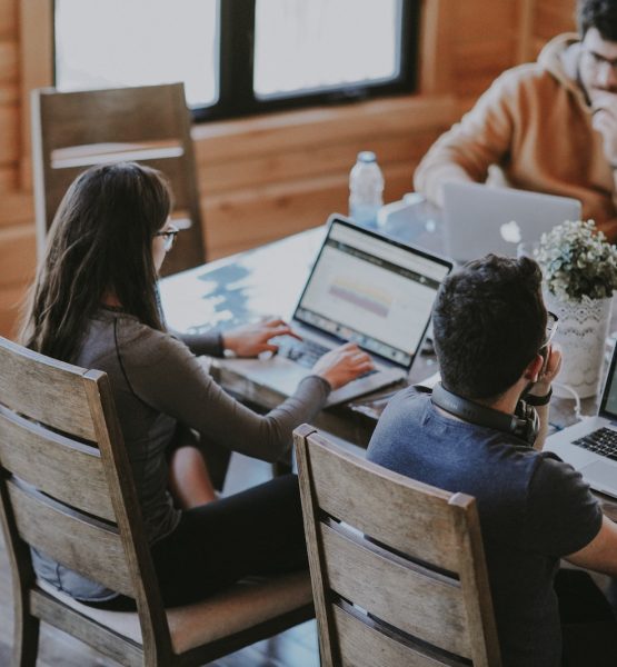 selective focus photography of woman and man using MacBook Pro on table